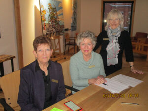 Three women at a registration table